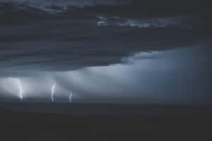 三道閃電照亮了海洋上空的暴風雨之夜。 — MacBook Pro 壁紙