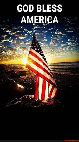 日落時分海灘上的美國國旗，附有文字 god bless america