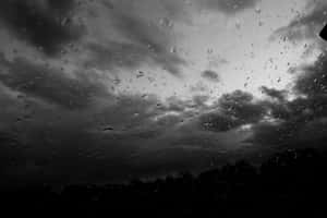 車窗上的雨滴，俯瞰暴風雨天際和深色樹木。