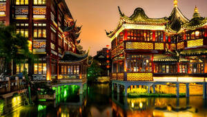夜間亮燈的傳統中式建築倒映在寧靜的運河中。 — 唐人街 GIF 壁紙