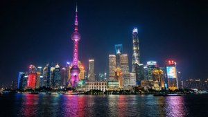 夜晚的上海天際線，燈火通明的摩天大樓和倒映在河中的東方明珠塔。