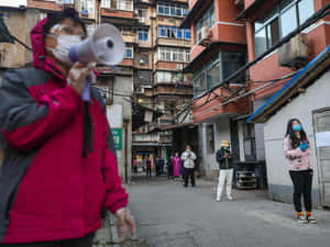 喺擠迫嘅小巷入面，戴住口罩嘅人對住大聲公大叫 — 唐人街 GIF 壁紙
