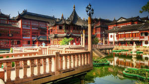 傳統中式庭院，有紅色建築和池塘上的石橋。 — 唐人街 GIF 壁紙