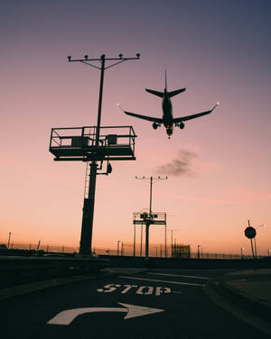 日落時分飛機在機場降落，可見停車標誌。