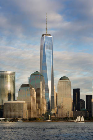 紐約市的One World Trade Center摩天大樓，在陰天下的水面上有帆船。