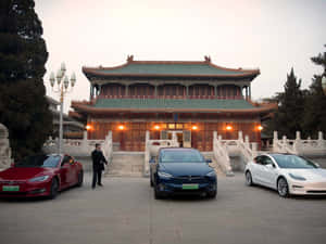 三輛Tesla電動車在黃昏時停在一座傳統中國寺廟前。 — 中國 壁紙