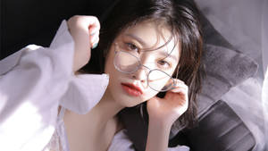 戴眼鏡的年輕女子在柔和光線下躺在床上 — 模特兒 GIF 壁紙