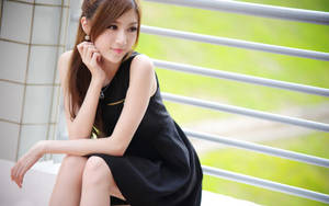 年輕女士穿黑色連衣裙坐在陽台欄杆上，綠色背景