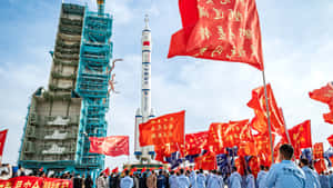 人群在晴朗天空下的火箭發射場揮舞紅旗。 — 唐人街 GIF 壁紙