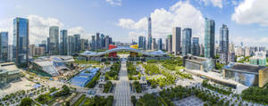 現代城市天際線，高聳玻璃建築和綠色公園，陽光普照。