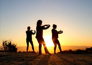三個女性在沙漠日落時以剪影練習武術。