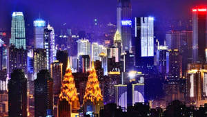 一個充滿活力的夜景城市，燈火通明的摩天大樓閃爍著藍色、紫色和金色。 — 唐人街 GIF 壁紙