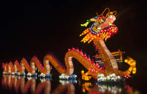 一盞發光的龍燈在夜間漂浮在水面上，映出五彩斑斕的倒影。 — 中文 壁紙