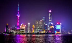 夜晚的上海天際線，燈火通明的塔樓和河流倒影。
