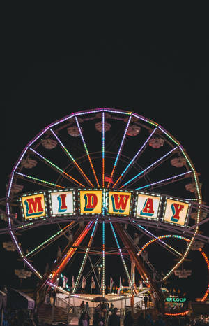 摩天輪在夜晚於遊樂園中帶有「MIDWAY」標誌發光。 — Honor MagicPad 3 Pro 12.3 壁紙