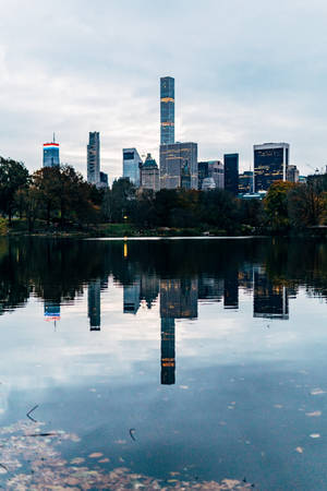 中央公園湖泊倒映曼哈頓天際線與秋樹