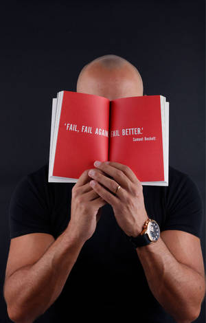 男人拿著打開的紅色書，上面有引文 fail fail again fail better