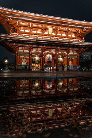 夜晚水坑中倒映的燈火通明的日本寺廟大門。