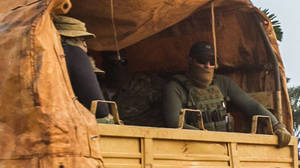兩名身穿軍用裝備的士兵在迷彩卡車車斗內。