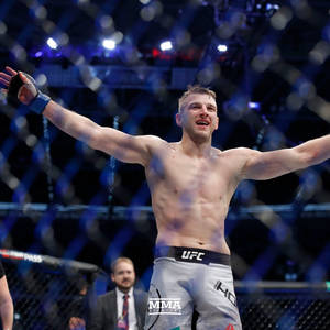 MMA拳手在八角籠中高舉雙臂慶祝勝利。