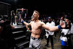 UFC拳手在八角籠中伸展雙臂慶祝勝利。