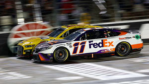 兩輛NASCAR賽車在夜間以動態模糊競速。