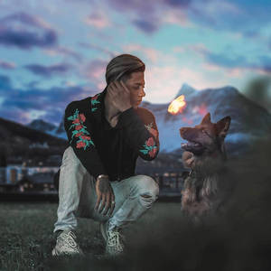 男人和德國牧羊犬在暮色中的山間草原上與蝴蝶共享寧靜時刻。 — 德國牧羊犬 壁紙