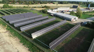烈日下工廠建築附近草地上的太陽能電池板行。