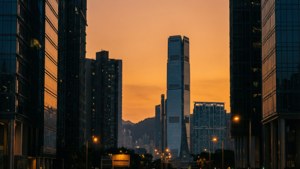 日落時分的現代城市天際線，高聳的玻璃建築和遠山 — 香港 壁紙