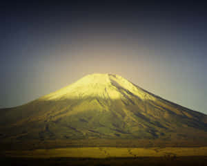 富士山被日出照亮，積雪的山頂和漸變色的天空。