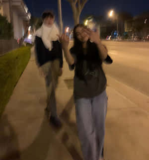 兩個人在夜間於行人路上行走，帶有動態模糊效果。