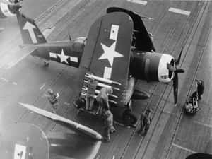 水手在航空母艦甲板上維修二戰戰鬥機。