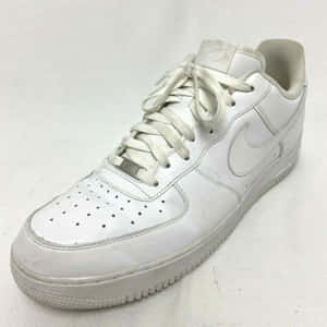 磨損的白色Nike Air Force 1運動鞋，皮革有刮痕，鞋帶骯髒。