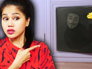 紅衣女性指著蓋伊·福克斯面具畫作，有戴黃色手套的手。