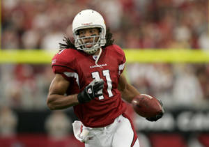 足球運動員穿著紅色 Cardinals 制服持球奔跑。 — 聖路易紅雀 壁紙