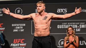 UFC戰士Gustafsson在稱重活動前於磅秤上擺姿勢，擂台女郎鼓掌。