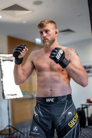 赤裸上身的MMA拳手穿著UFC短褲和手套在健身房擺姿勢。