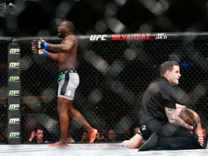 UFC拳手在八角籠中慶祝勝利，裁判照顧對手。