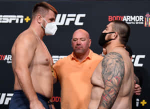 兩名赤裸上身的UFC拳手戴著口罩，在稱重時與裁判面對面站立。