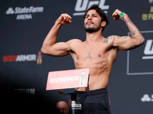 UFC拳手在秤重活動中屈起手臂，背後有BodyArmor標誌。
