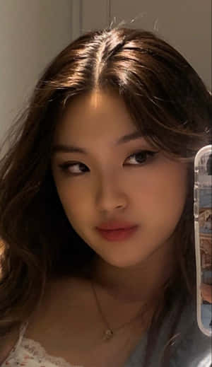 年輕女性在溫暖的室內燈光下用手機自拍。