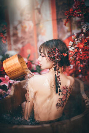 戴著花卉頭飾的女士將水倒入被紅花環繞的木浴盆中。