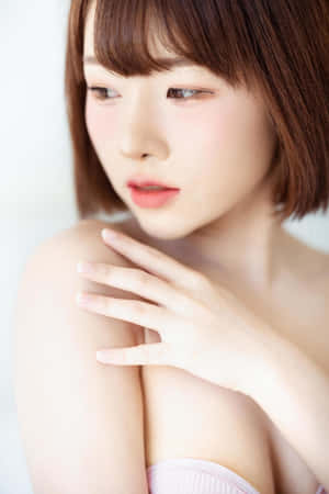 短棕髮的年輕女性在柔和光線中觸碰她的肩膀。 — 模特兒 GIF 壁紙