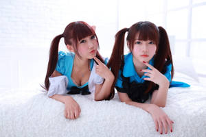 兩名動漫風格的女僕 cosplayer 在白色床上紮著辮子擺姿勢。