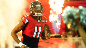 身穿紅色Falcons球衣的足球運動員穿過煙霧和煙火奔跑。