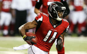 比賽期間身穿紅色 Falcons 制服帶球奔跑的足球運動員。