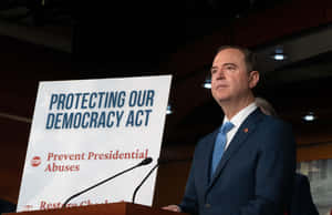 西裝男子在講台旁，標誌寫著「Protecting Our Democracy Act」。