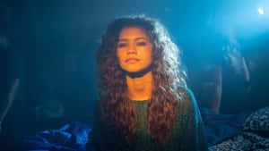 Zendaya 在演唱會中留著捲髮，處於藍色舞台燈光下。