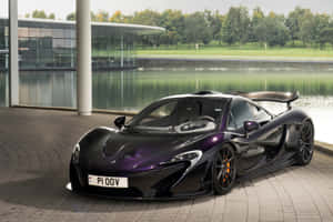 黑色McLaren P1跑車停泊在水邊和玻璃建築旁。