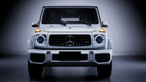 銀色 Mercedes-Benz G-Class SUV 在攝影棚環境中車頭燈亮起的前視圖。